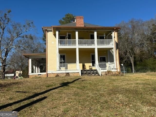 rear view of property featuring a porch, a yard, and a balcony