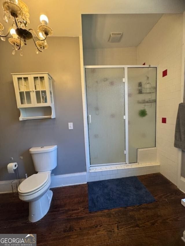 bathroom featuring a chandelier, wood-type flooring, toilet, and walk in shower