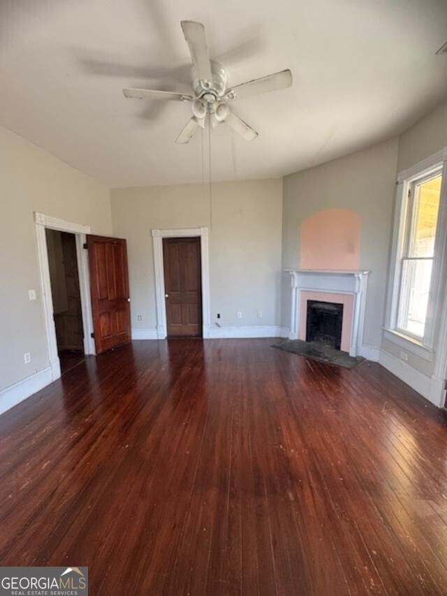 unfurnished living room featuring ceiling fan and dark hardwood / wood-style flooring