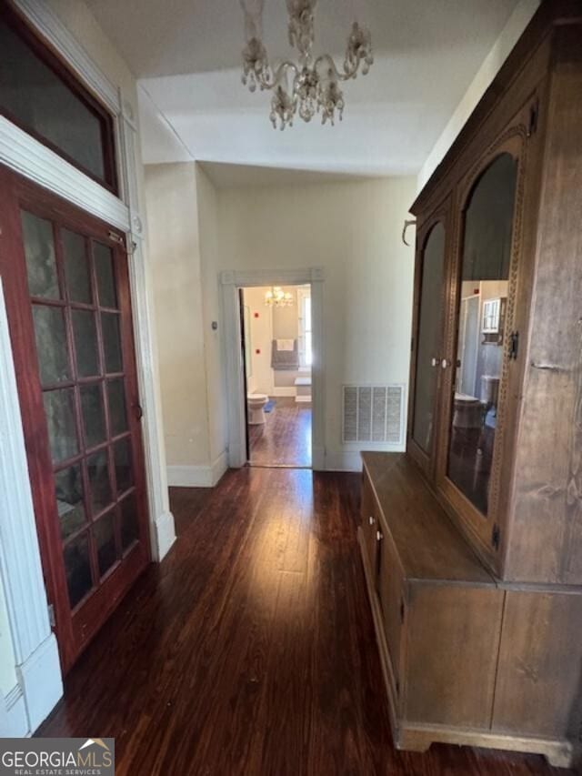 corridor with an inviting chandelier and dark wood-type flooring