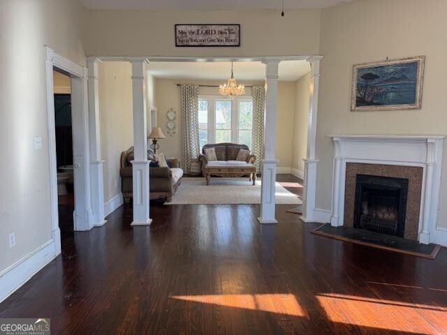 living room featuring dark hardwood / wood-style floors, ornate columns, and a chandelier