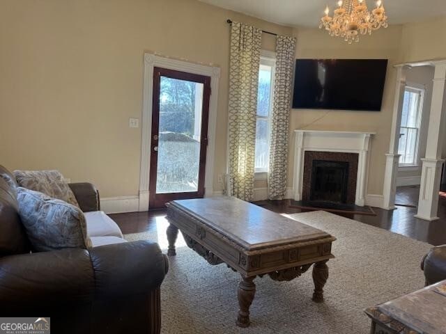 living room featuring plenty of natural light, a fireplace, a chandelier, and dark hardwood / wood-style floors