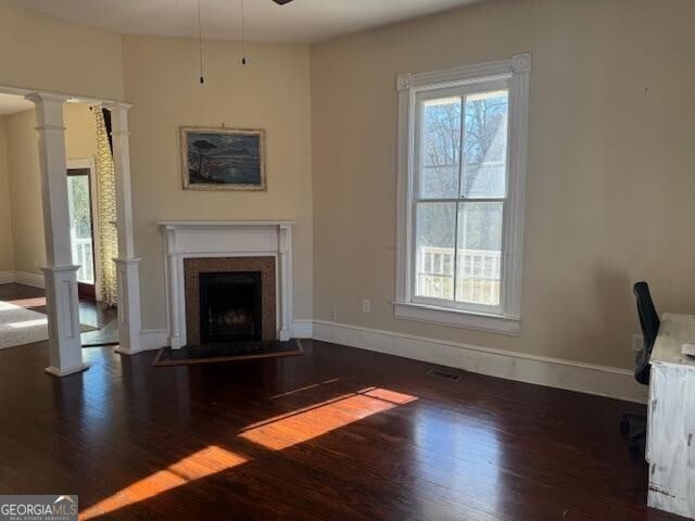 unfurnished living room with decorative columns, ceiling fan, and dark wood-type flooring