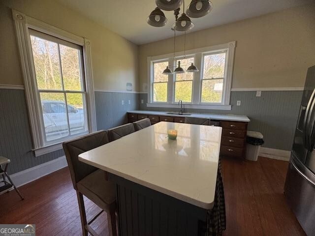 kitchen featuring stainless steel fridge, sink, pendant lighting, dark hardwood / wood-style floors, and a kitchen island