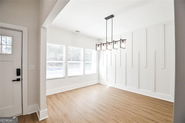 unfurnished dining area featuring plenty of natural light, light hardwood / wood-style floors, and a notable chandelier