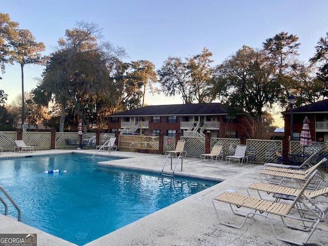 pool at dusk featuring a patio