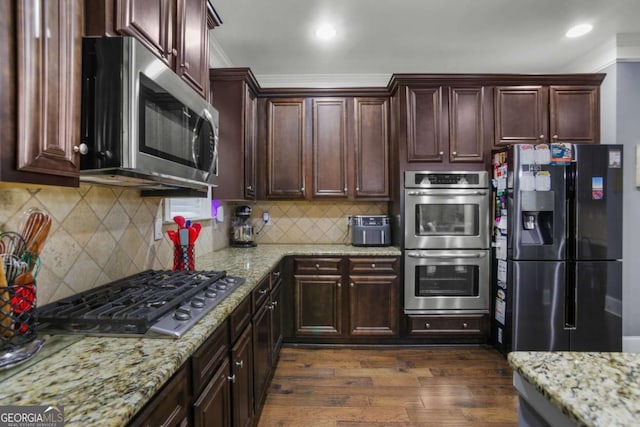 kitchen with decorative backsplash, light stone countertops, stainless steel appliances, and ornamental molding