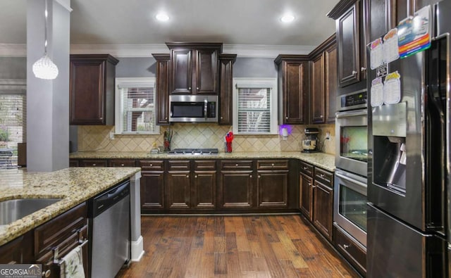 kitchen featuring light stone countertops, hanging light fixtures, dark hardwood / wood-style floors, decorative backsplash, and appliances with stainless steel finishes