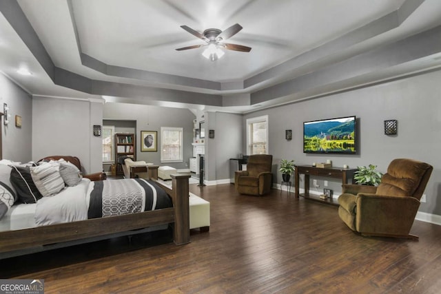 bedroom featuring ceiling fan, a raised ceiling, and dark wood-type flooring