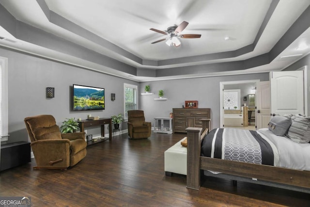 bedroom featuring a tray ceiling, ceiling fan, ensuite bathroom, and dark hardwood / wood-style floors