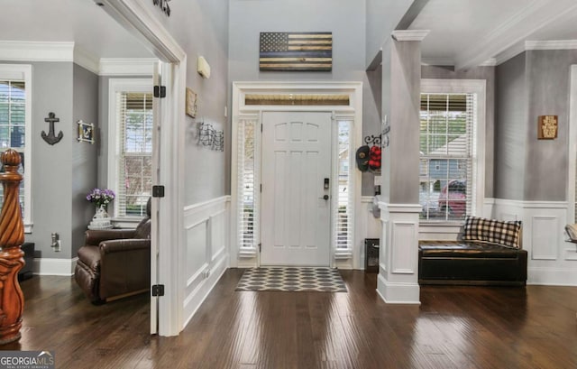 entrance foyer featuring dark hardwood / wood-style flooring, decorative columns, and crown molding