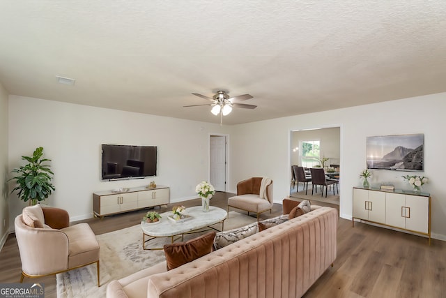 living room with a textured ceiling, hardwood / wood-style flooring, and ceiling fan