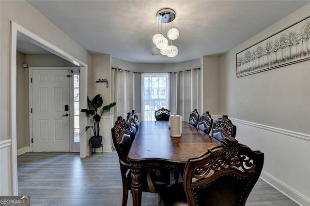 dining room featuring wood-type flooring and an inviting chandelier