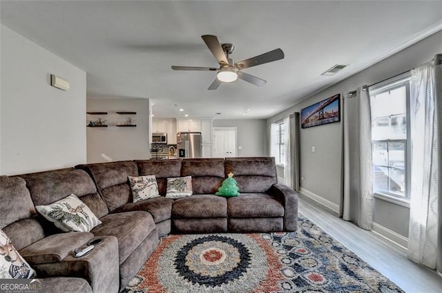 living room with light hardwood / wood-style flooring and ceiling fan