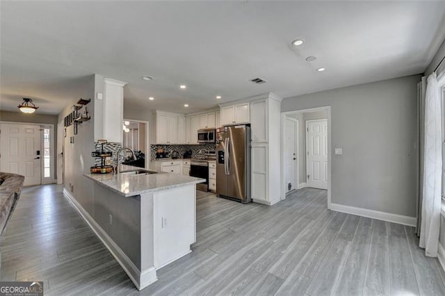 kitchen featuring white cabinetry, sink, stainless steel appliances, backsplash, and kitchen peninsula