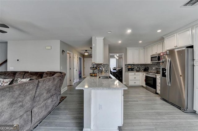 kitchen with tasteful backsplash, stainless steel appliances, ceiling fan, sink, and white cabinetry