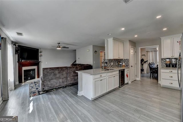 kitchen featuring wine cooler, white cabinetry, light hardwood / wood-style flooring, and decorative backsplash