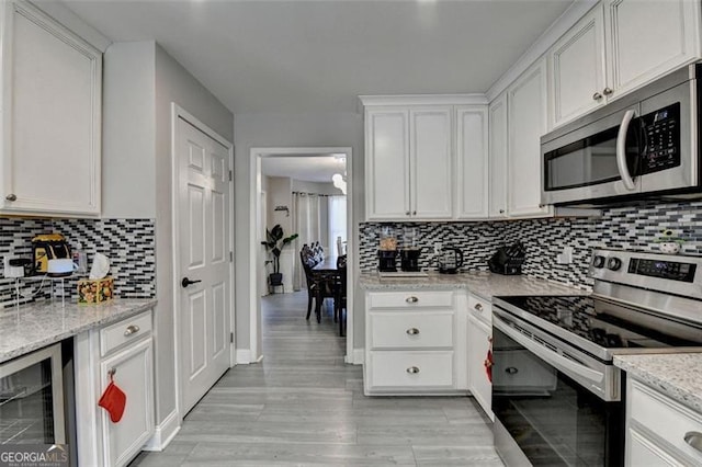 kitchen with white cabinets, stainless steel appliances, wine cooler, and light stone counters