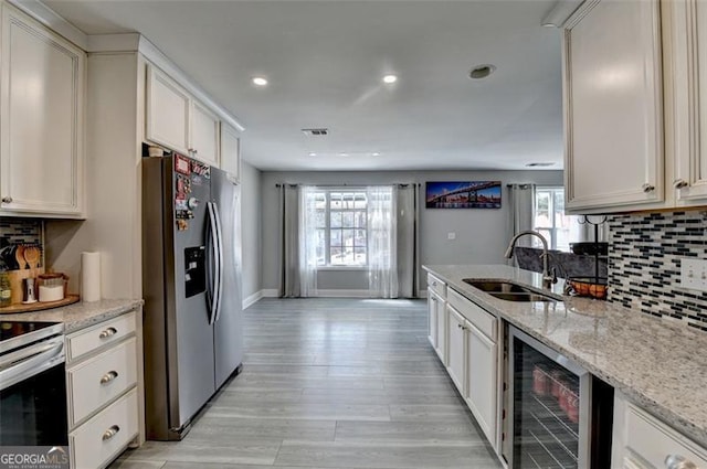 kitchen featuring beverage cooler, light stone countertops, sink, and appliances with stainless steel finishes