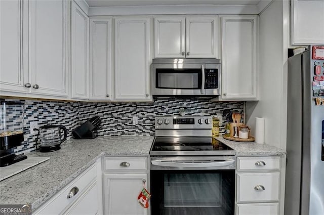 kitchen with white cabinets, stainless steel appliances, light stone counters, and tasteful backsplash