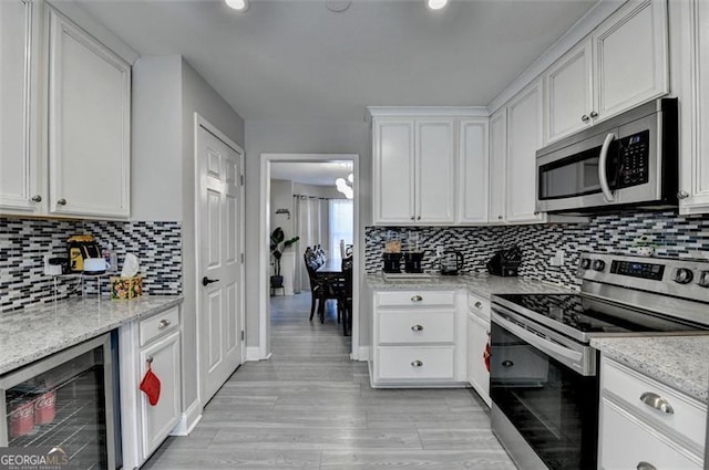 kitchen with white cabinetry, beverage cooler, and appliances with stainless steel finishes