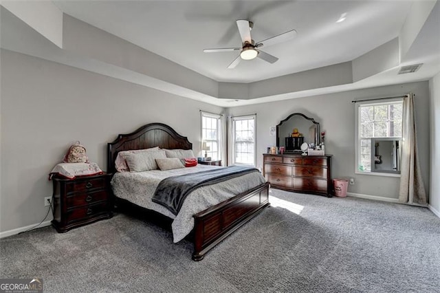 bedroom featuring carpet flooring, ceiling fan, a raised ceiling, and multiple windows