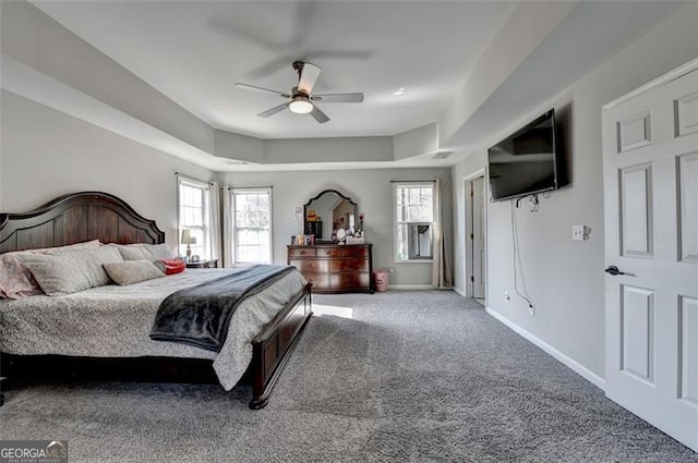 carpeted bedroom featuring a raised ceiling and ceiling fan