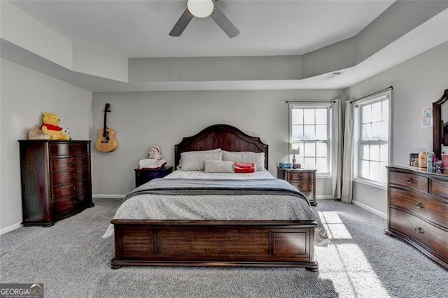 bedroom with a tray ceiling, ceiling fan, and light carpet