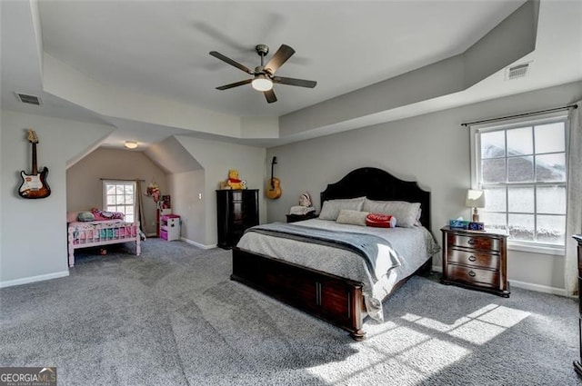 carpeted bedroom with a raised ceiling, multiple windows, and ceiling fan