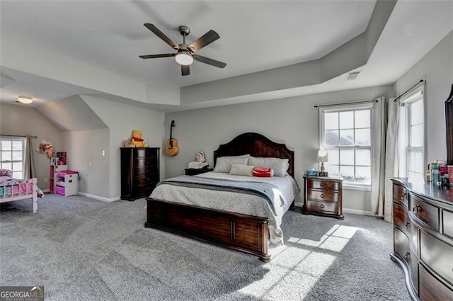 bedroom featuring a raised ceiling, ceiling fan, and light colored carpet