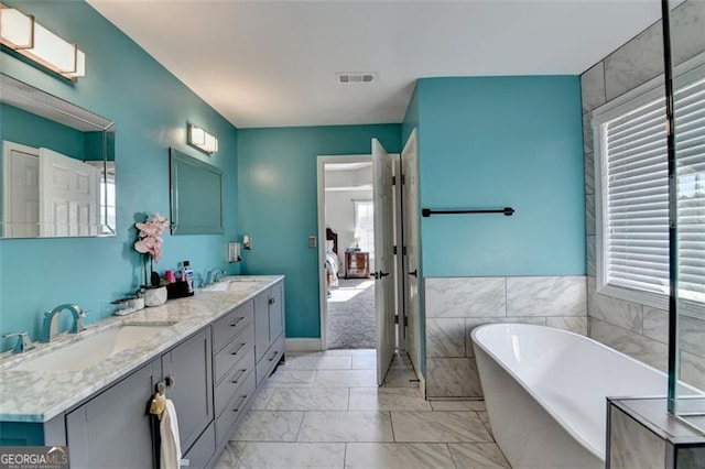 bathroom featuring vanity, a tub, and tile walls