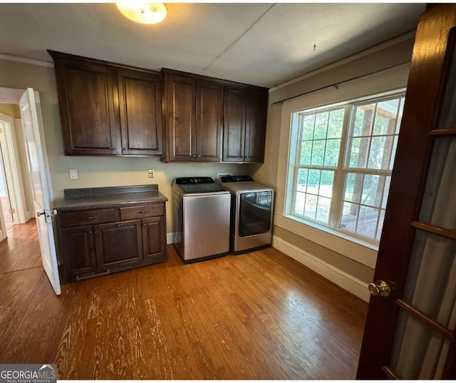 laundry area featuring cabinets, light wood-type flooring, crown molding, and washing machine and dryer