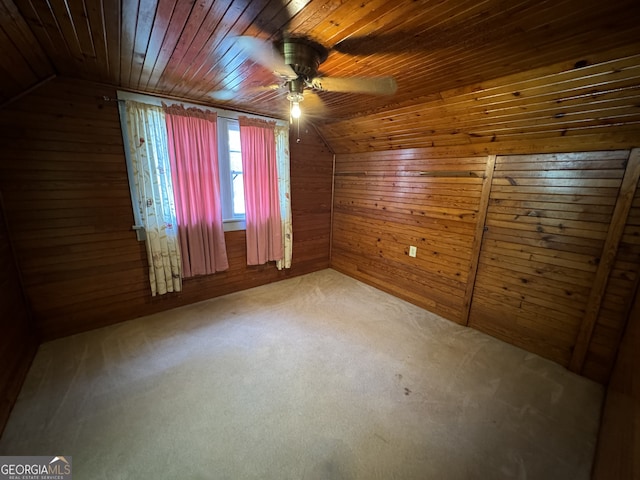 spare room featuring carpet, vaulted ceiling, ceiling fan, wooden walls, and wooden ceiling