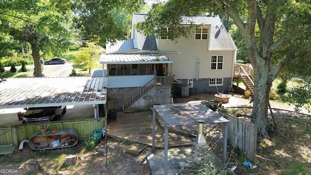 back of house with central air condition unit, a wooden deck, and a sunroom