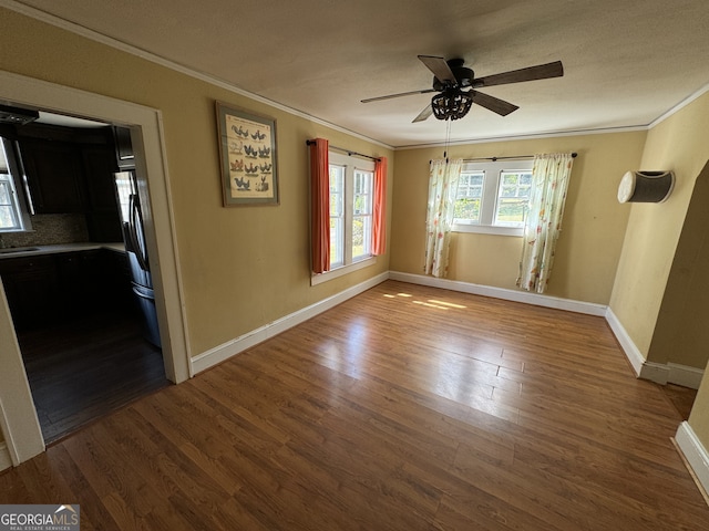 unfurnished room featuring wood-type flooring, ceiling fan, ornamental molding, and sink