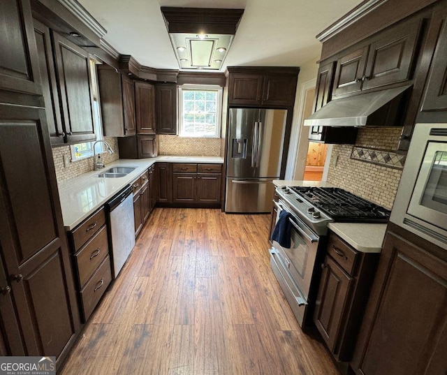 kitchen featuring hardwood / wood-style floors, backsplash, sink, dark brown cabinets, and stainless steel appliances