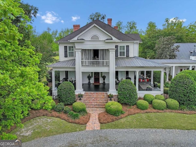 neoclassical / greek revival house featuring a porch, a balcony, and a front yard