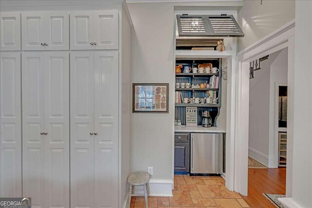 interior space featuring fridge, wine cooler, baseboards, and stone finish flooring