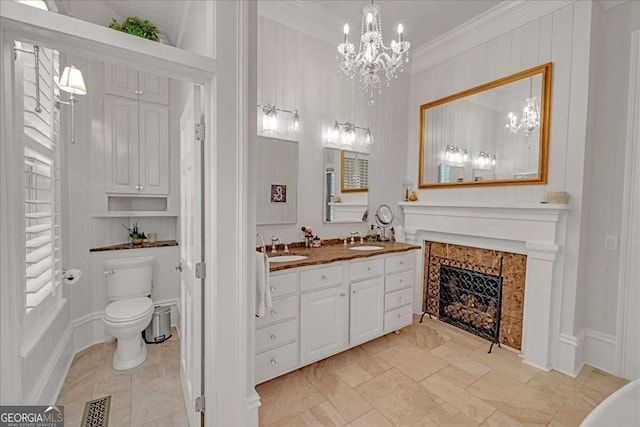 bathroom featuring vanity, a tile fireplace, an inviting chandelier, crown molding, and toilet