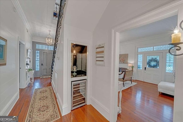 entrance foyer with crown molding, hardwood / wood-style floors, beverage cooler, and plenty of natural light