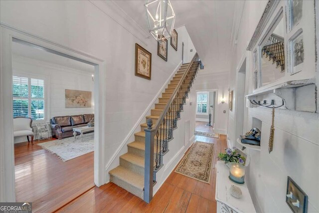 stairs with baseboards, hardwood / wood-style floors, and crown molding