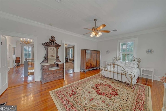 bedroom featuring visible vents, ceiling fan with notable chandelier, ornamental molding, and light wood finished floors