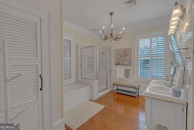 bathroom with ornamental molding, wood-type flooring, independent shower and bath, and an inviting chandelier