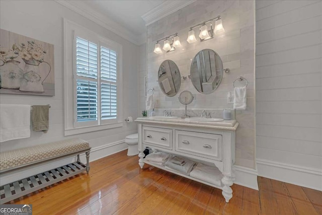 full bathroom with crown molding, toilet, double vanity, hardwood / wood-style flooring, and a sink