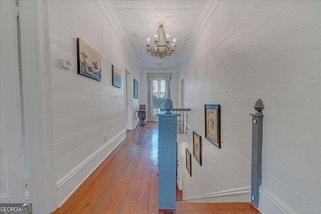 hall with an upstairs landing, crown molding, an inviting chandelier, and hardwood / wood-style flooring