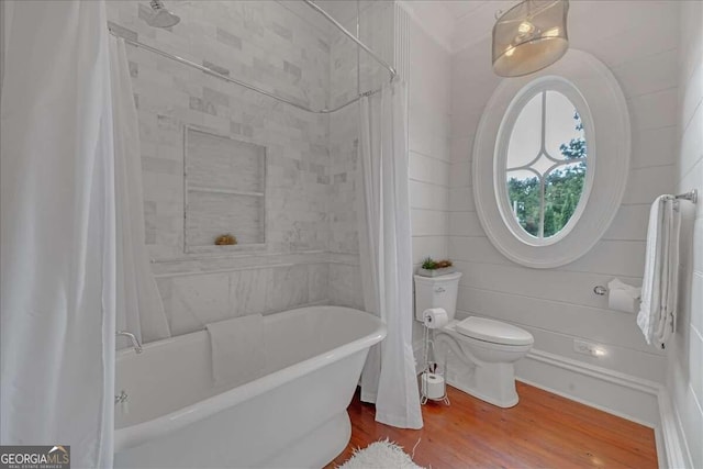 bathroom featuring toilet, hardwood / wood-style flooring, and shower / tub combo with curtain