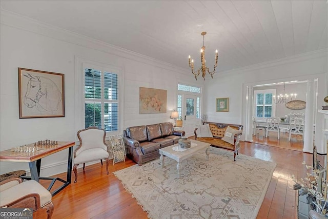 living room with light wood finished floors, a chandelier, and ornamental molding