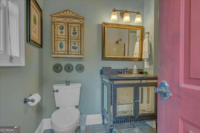 bathroom featuring baseboards, toilet, and vanity