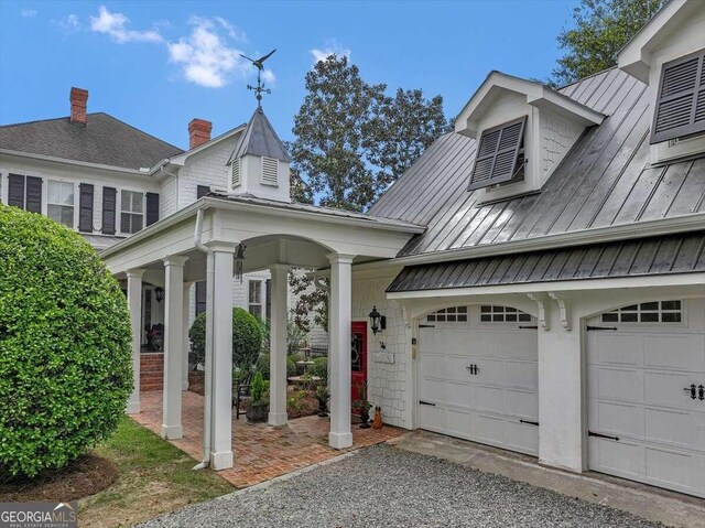 view of property exterior featuring a garage, driveway, metal roof, and a standing seam roof
