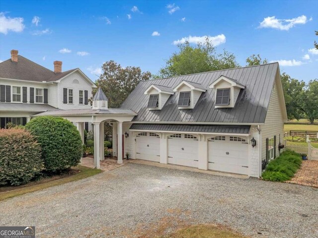 view of front of home featuring a standing seam roof, fence, driveway, and metal roof